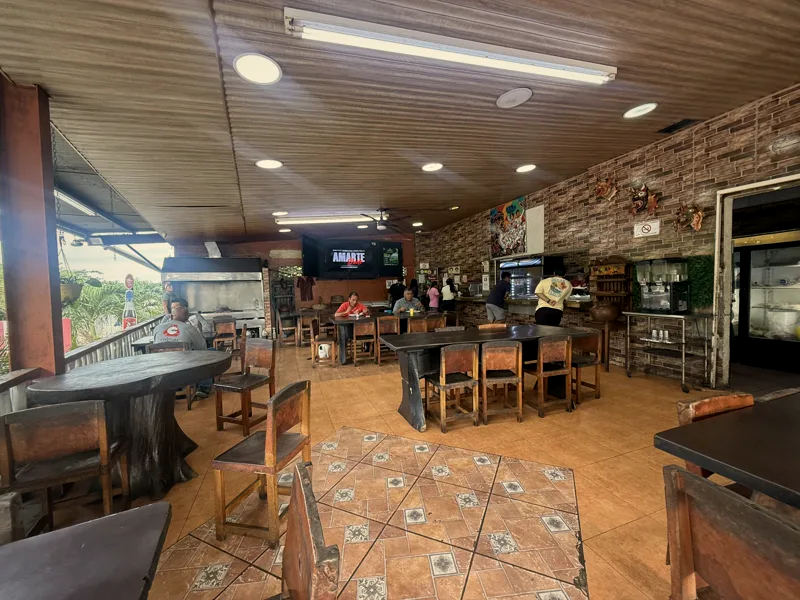 Mesas de madera, pared de ladrillo y piso de barro del comedor